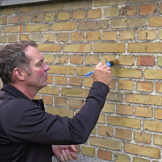 Trykk på mørtelen med en pensel Trykk på mørtelen med en pensel